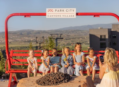 A group of children sit on a red bench under a 