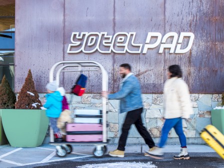 People walking by a hotel entrance sign 
