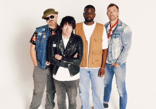 Four individuals in varied casual clothing, including denim and leather, stand against a plain backdrop.
