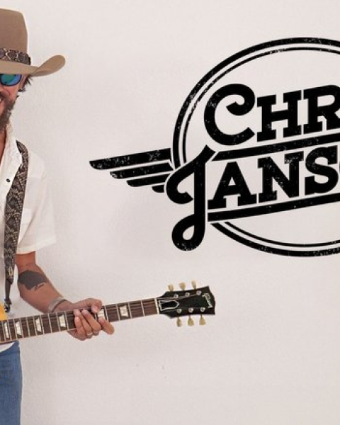A person with a guitar wearing a hat and sunglasses, next to a 