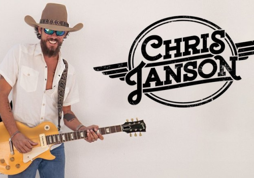 A person with a guitar wearing a hat and sunglasses, next to a 