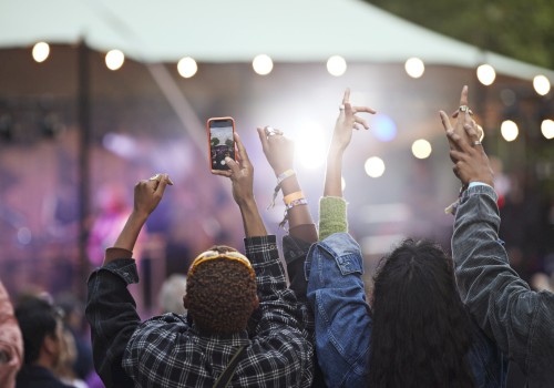 People at an outdoor concert, hands raised, enjoying the performance.