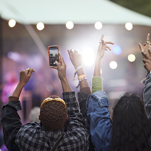 People at an outdoor concert, hands raised, enjoying the performance.